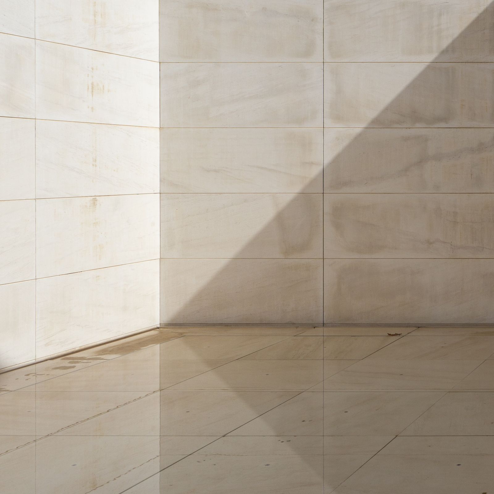 Detalhe de piso e rodapé em mármore claro com luz natural